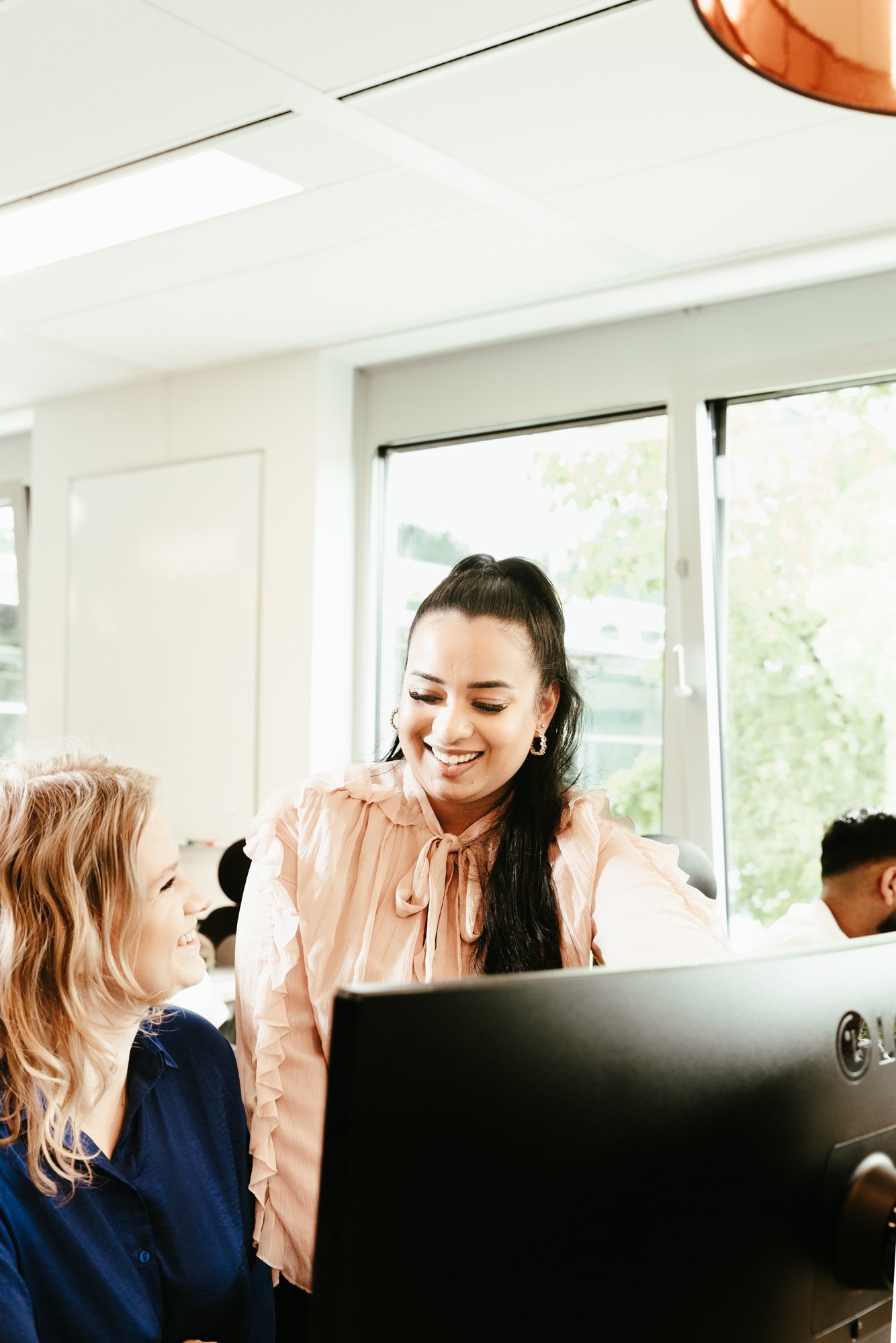 Een vrouwelijke collega die haar collega helpt met applicaties